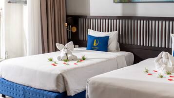 A hotel room with two beds, a headboard, and a painting on the wall.