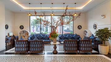 A lobby with a reception desk, seating area, decorative plants, and a patterned floor.