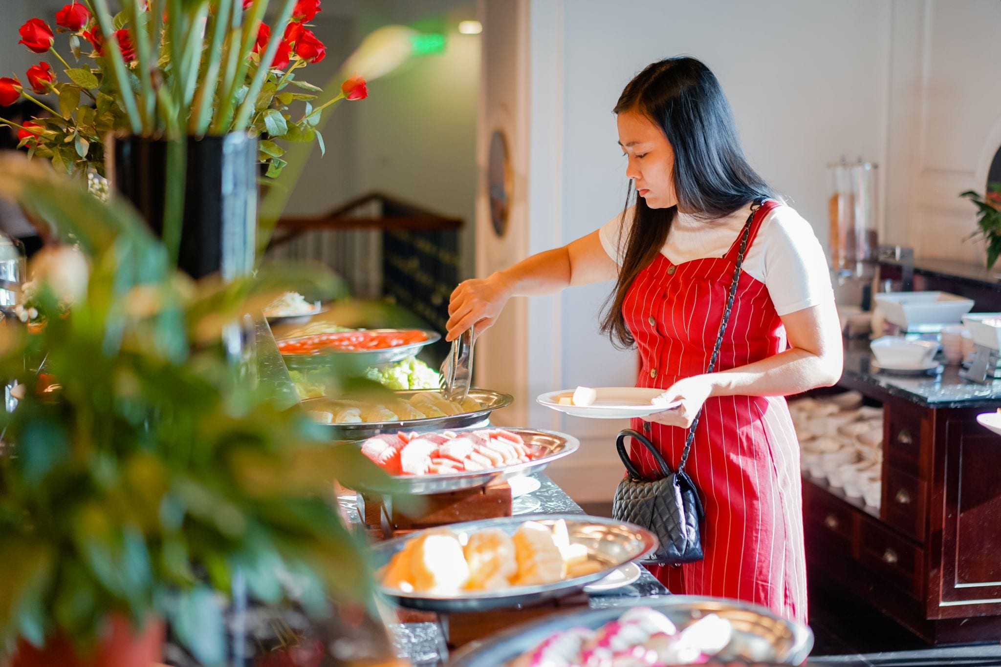 A buffet setup with various food items and a person serving.