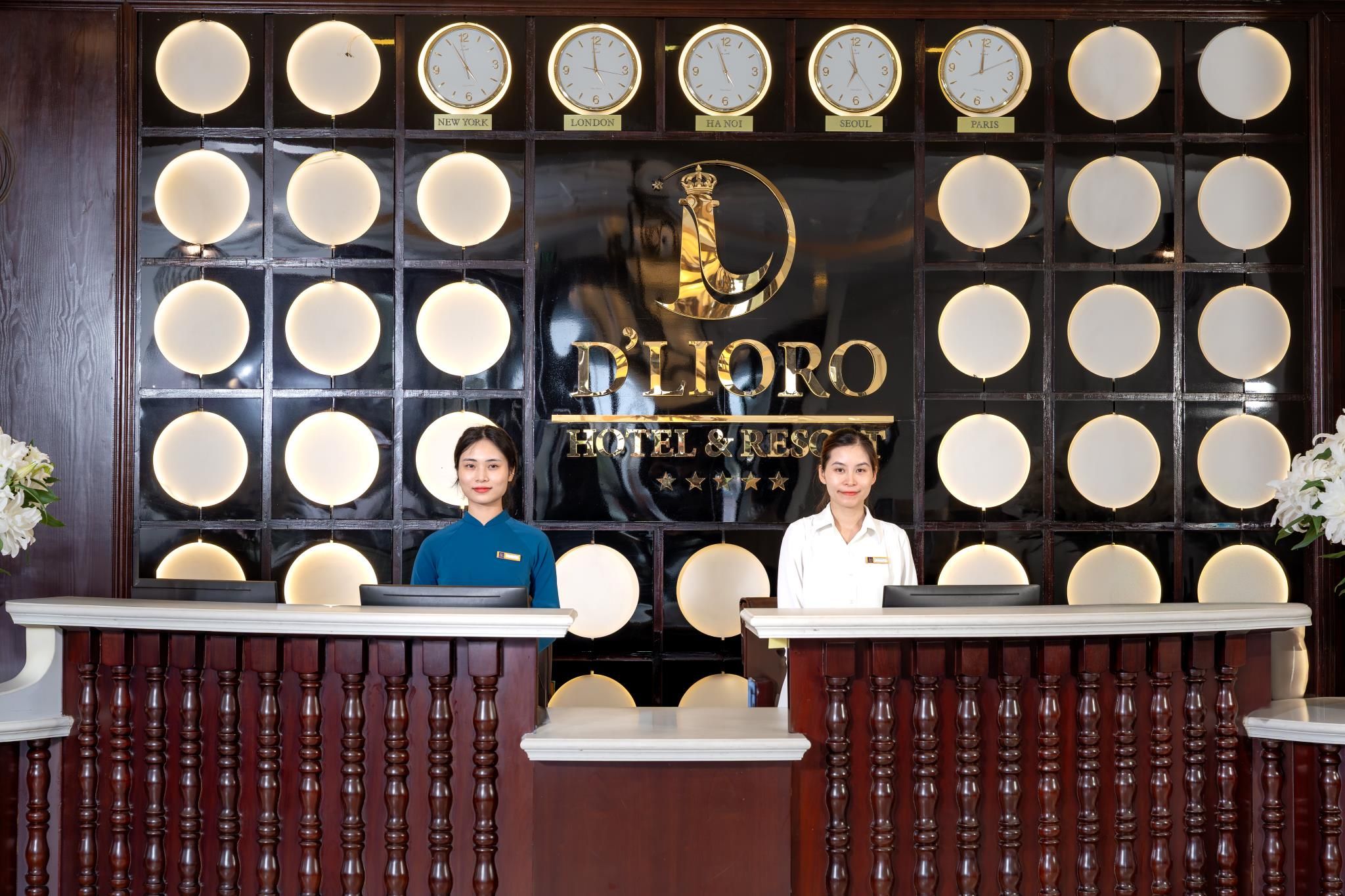 A hotel reception desk with multiple clocks displaying different city times, a reception area with two staff members, and a large emblem above the reception desk.