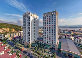 Un hotel moderno de gran altura con varios pisos, un letrero llamativo en la parte superior y vistas del paisaje urbano circundante.