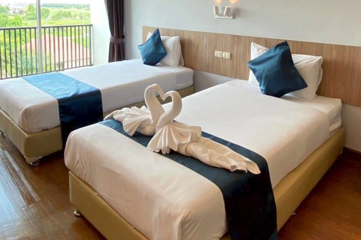 A hotel room with two beds, a balcony, and a view of the outdoors.