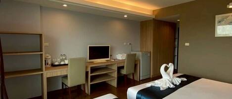 A hotel room with two beds, a desk with a computer, a chair, and a TV.