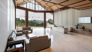 A spacious lobby with a reception desk, seating area, and large windows offering a view of the outdoors.