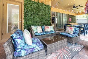 A patio area with wicker furniture, a green wall, and string lights. - Pool Movies|Game Room|Movie Theater|Private Lot (Kissimmee)