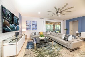 A modern living room with a sectional sofa, a coffee table, and artwork on the walls. - Pool Movies|Game Room|Movie Theater|Private Lot (Kissimmee)