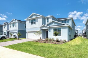 A two-story residential building with a garage, a driveway, and a well-maintained lawn. - Breezy Palms|Spectacular NEW Villa|NEW WOW Resort (Clermont)