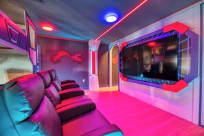 Ein moderner Kinoraum mit einer Reihe bequemer, roter Ledersitze, einer großen Leinwand und Neonlicht-Akzenten.