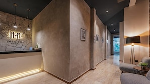 A hotel reception area with a stone wall, a reception desk, and a seating area with a lamp. - Hotel Mexico (Mérida)