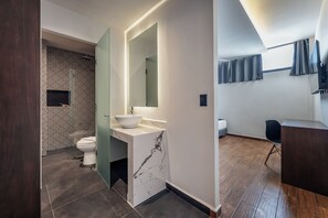 Une salle de bain moderne avec un lavabo blanc, un grand miroir et des toilettes.
