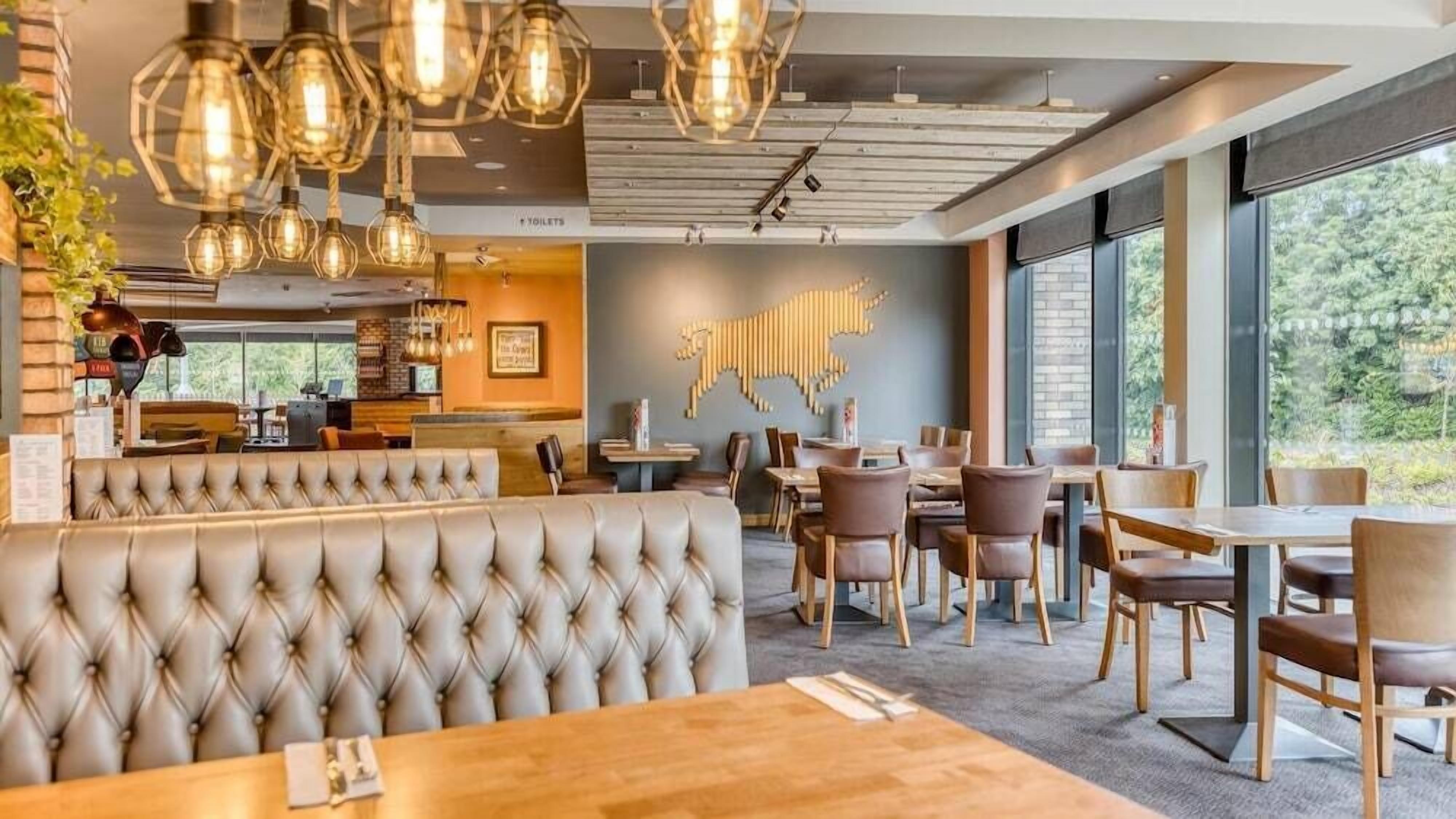 A restaurant with a bar area, seating arrangements, and a large window providing a view of the outdoors.