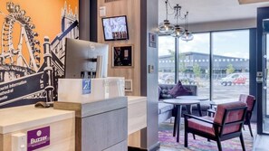Ein Hotel-Empfangsbereich mit einem Schreibtisch, einem Computer und Blick durch große Fenster nach draußen.