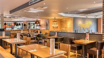 A restaurant interior with wooden tables, chairs, and a counter area.