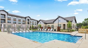 A swimming pool with lounge chairs and a building with multiple floors and balconies. - Modern Apt I Prime Location & Workspace (Sherman)
