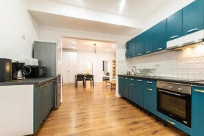 Une cuisine moderne avec des armoires de couleur turquoise, un four noir et un plancher en bois.