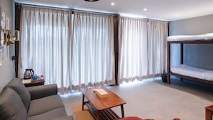 A room with a bunk bed, a sofa, a table, and curtains. - Anchaviyo Resort (Vada)