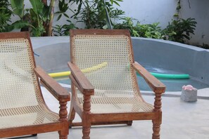 Two wooden chairs with woven seats and backs, placed on a concrete surface with a pool and plants in the background. - Catcus Reef Ahangama (Ahangama)