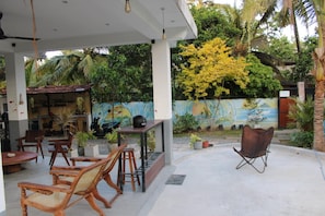 Uma área de estar ao ar livre com móveis de madeira e um mural na parede.