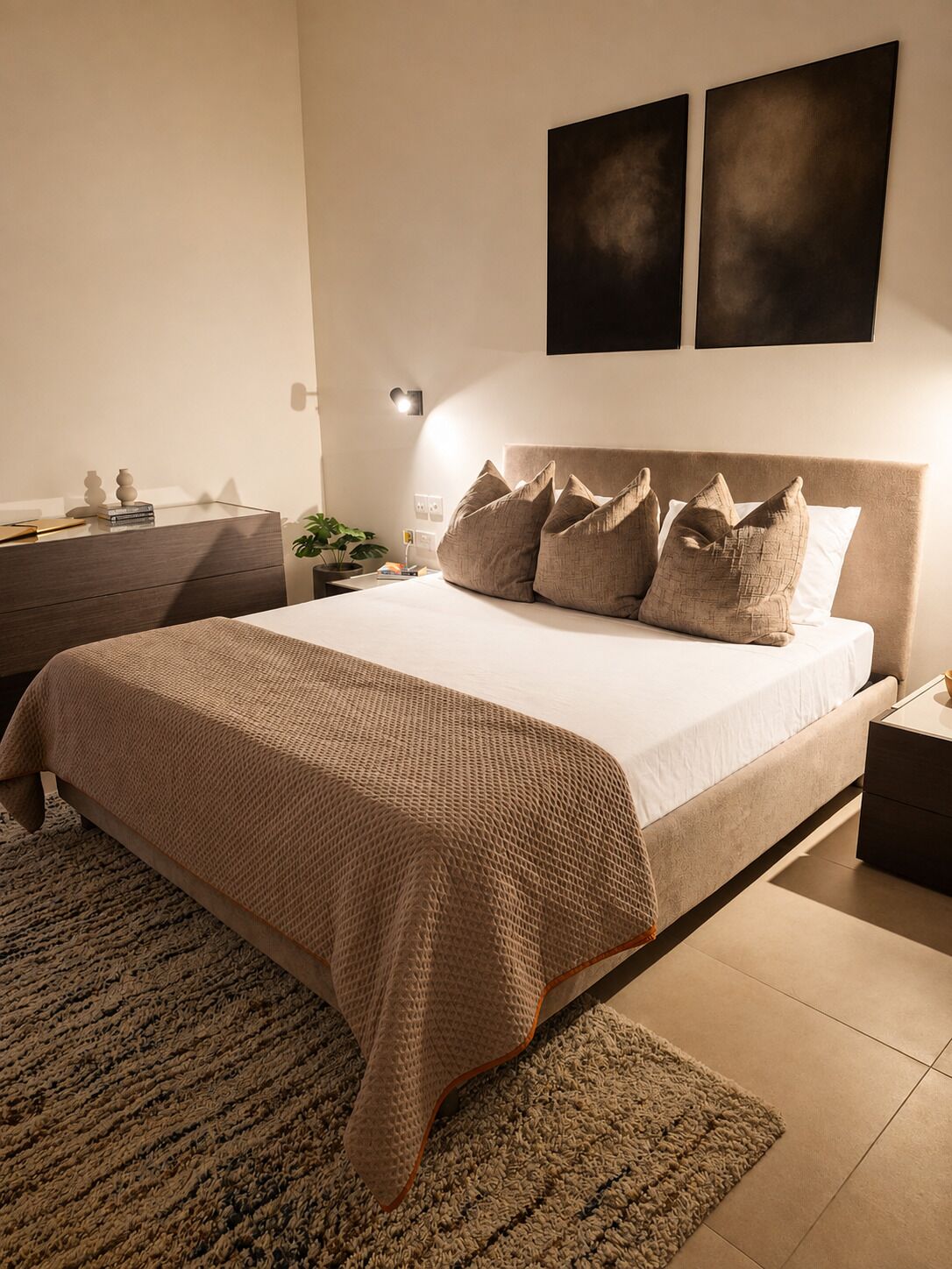 A bedroom with a bed, bedside tables, a dresser, and a wall-mounted light.