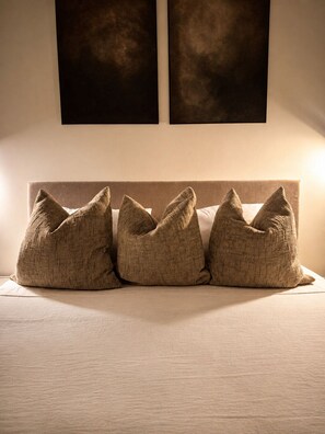 Una cama con cabecera y tres almohadas.