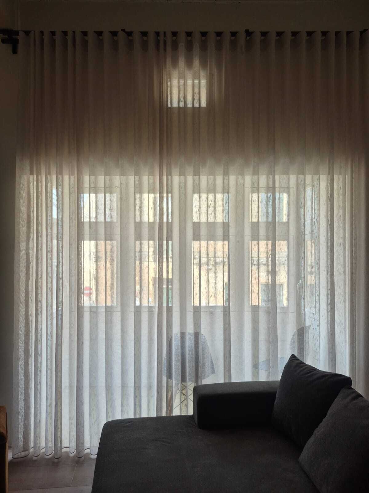 Habitació amb un llit, una cadira i una finestra amb cortines.