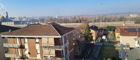 A multi-story residential building with balconies, a parking area, and a clear view of the surrounding neighborhood.