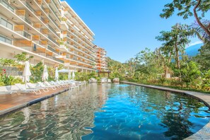 Ein Hotel mit mehreren Balkonen, einem Schwimmbad und üppiger Bepflanzung.