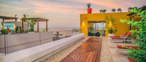 Une terrasse sur le toit, dotée d’une plateforme en bois, d’espaces aménagés pour s’asseoir et de plantes en pot.