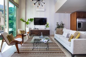 A modern living room with a large TV, comfortable seating, and a kitchen area. - Designer Penthouse at V177 | Walk to Beach 1BD Condo for rent in Old Town, Puert (Puerto Vallarta)