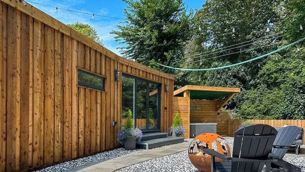 A modern wooden building with a glass door entrance, outdoor seating with Adirondack chairs, and a fire pit. - 1 bedroom accommodation in Stranraer (Stranraer)