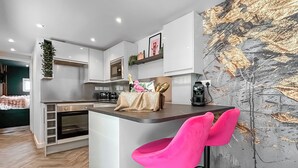 A modern kitchen with a central island, bar stools, and a large abstract painting on the wall. - 1 bedroom accommodation in Stranraer (Stranraer)