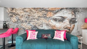 A teal sofa with two pillows, a patterned throw pillow, and a wall with a large abstract painting. - 1 bedroom accommodation in Stranraer (Stranraer)