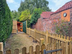 Eine Ziegelwand, ein Holzzaun und ein Gartenbereich mit einer Holzhütte.