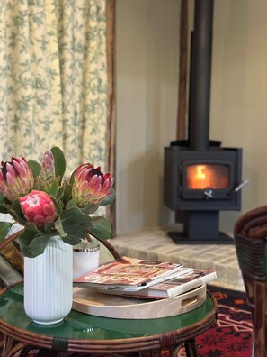 A room with a fireplace, a vase with flowers, and a table with magazines.