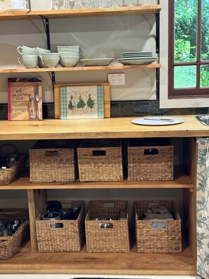 A kitchen shelf with various kitchenware and a cookbook.