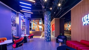 A modern lounge area with seating, a reception desk, and a bookshelf.