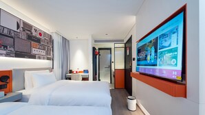 A hotel room with a large bed, a desk, and a TV mounted on the wall displaying a menu.
