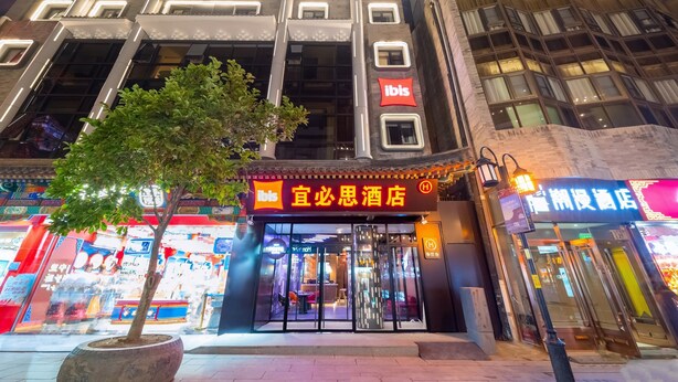 A hotel with a modern facade, large windows, and a prominent 'ibis' sign.