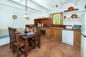 A kitchen with a dining table, chairs, a stove, a microwave, and a dishwasher. - Villa in Pollensa With Mountain Views & Pool (Pollença)