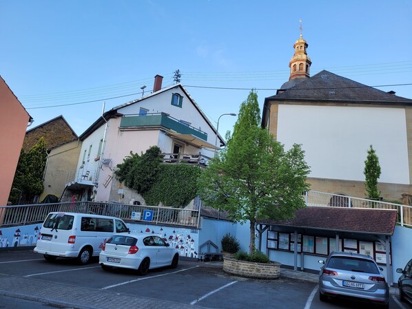 Um edifício com uma torre imponente e um estacionamento com vários carros.