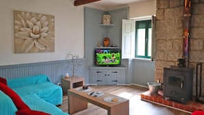 A living room with a fireplace, a television, and a large flower painting on the wall.