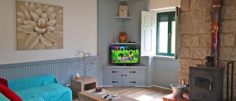 A living room with a fireplace, a television, and a large flower painting on the wall.
