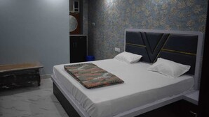 Quarto com cama, um banquinho, guarda-roupa e parede com padrão floral.