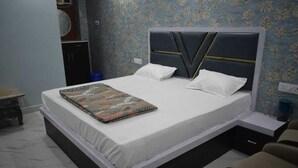 Uma cama com cabeceira, duas almofadas, mesa de cabeceira e uma cadeira.