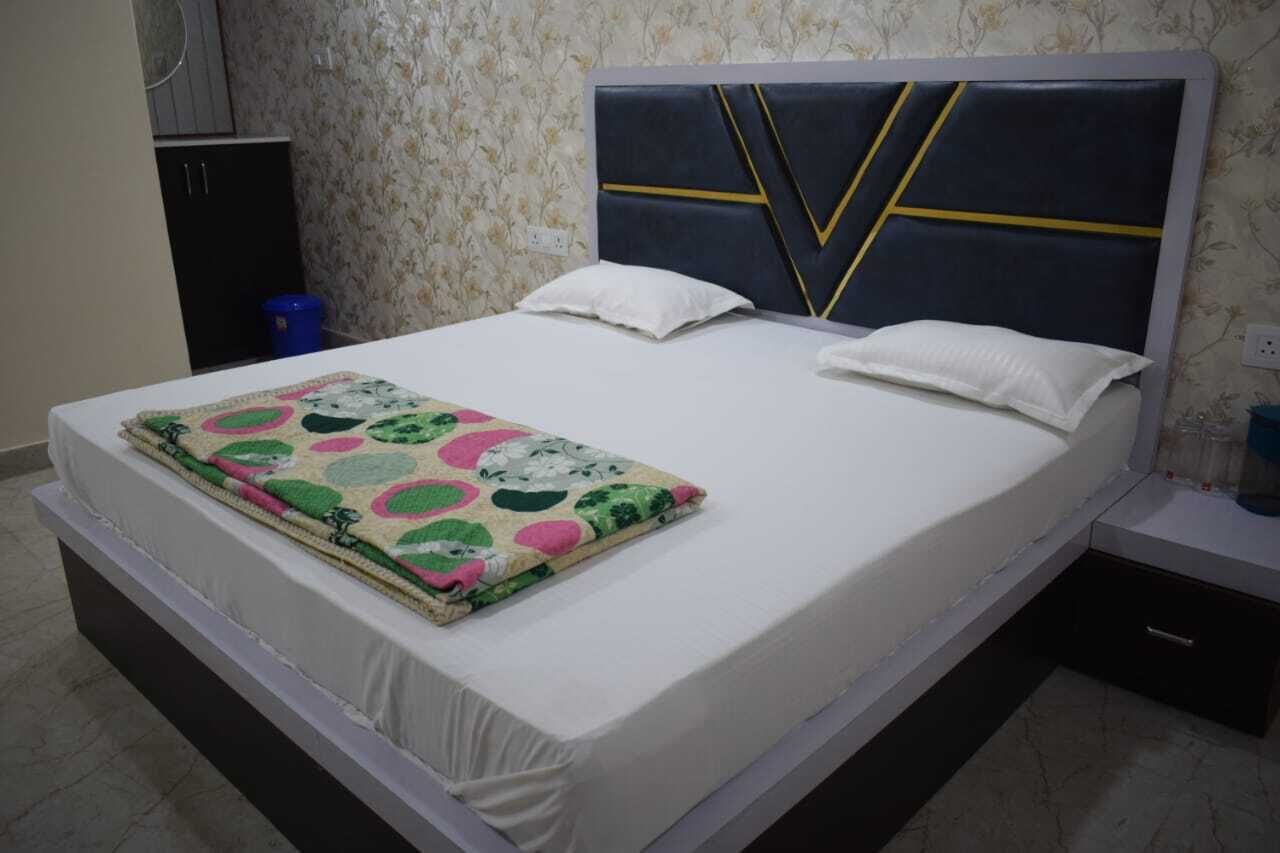 Una cama con colchón blanco, manta colorida y cabecera con diseños geométricos.
