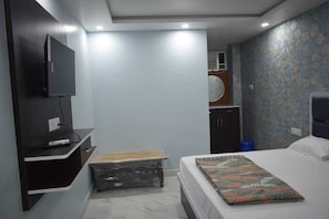 Une chambre à coucher avec un lit, un téléviseur fixé au mur, un petit banc et une armoire.