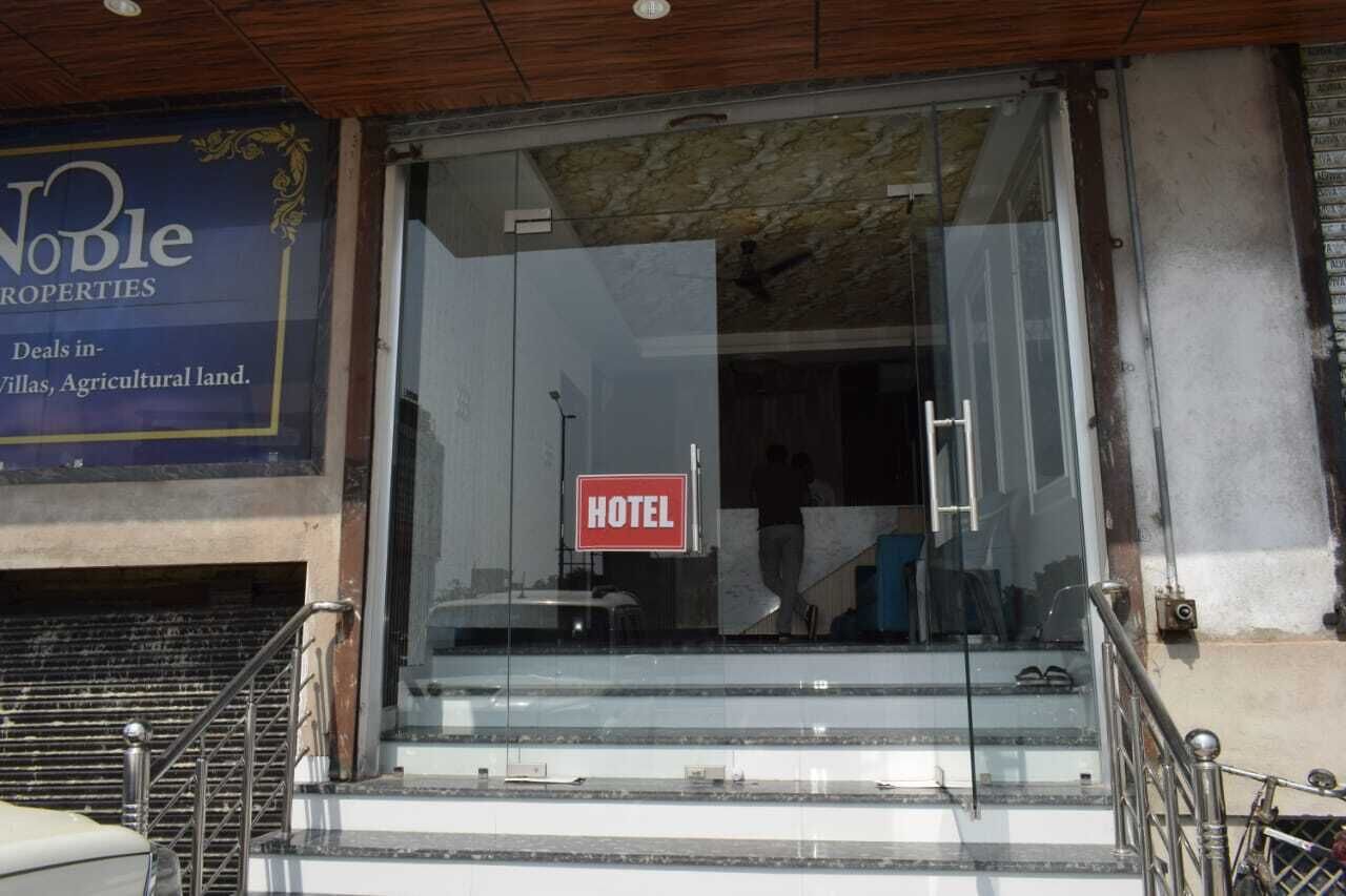 A hotel entrance with a glass door, a 'HOTEL' sign, and a sign for Noble Properties.