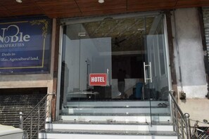A hotel entrance with a glass door, a 'HOTEL' sign, and a sign for Noble Properties. - Hotel Highway Crown (Kanpur)