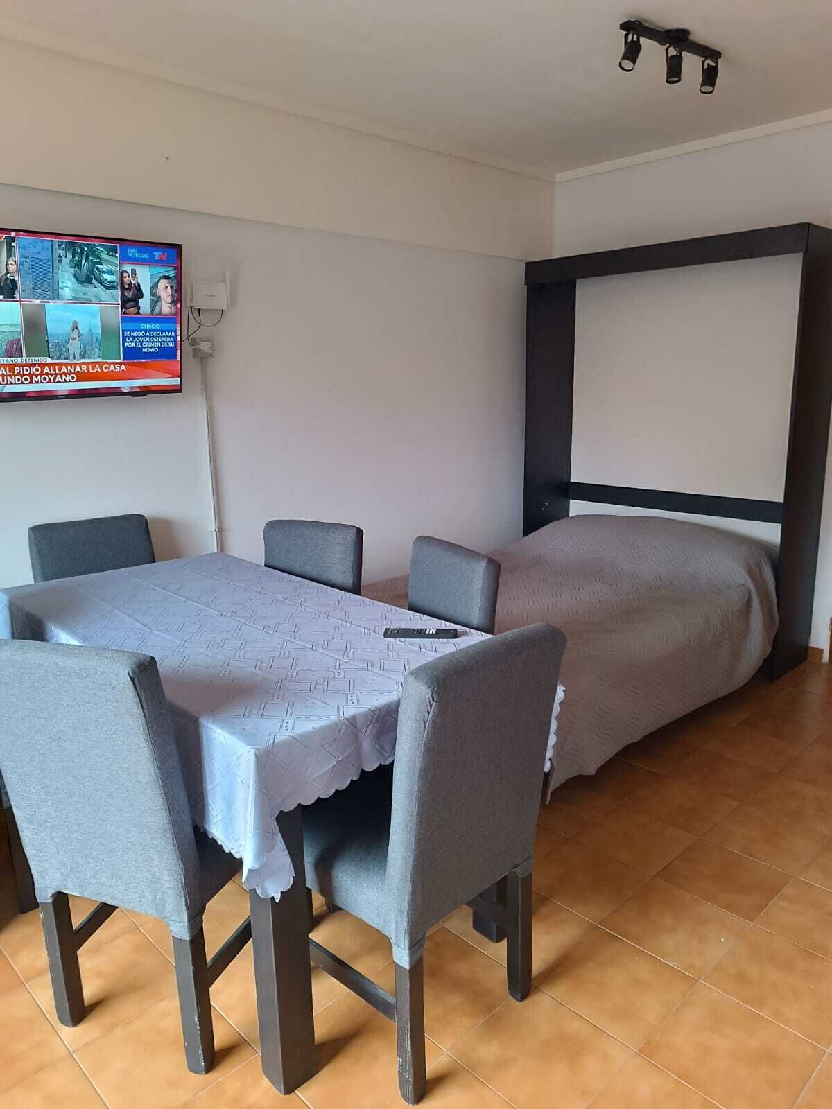 Une petite pièce comprenant un lit, une table avec des chaises et un téléviseur fixé au mur.