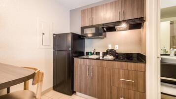 A compact kitchen with a refrigerator, microwave, stove, and wooden cabinets.